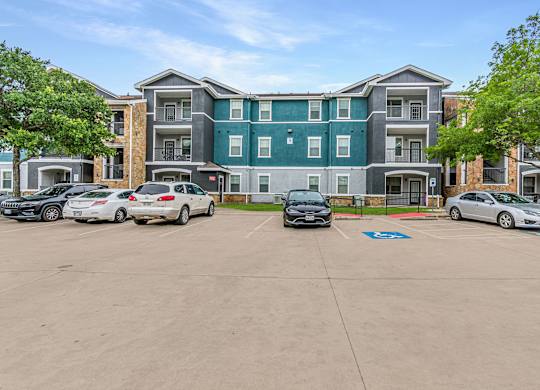 A parking lot in front of a multi-story apartment building.