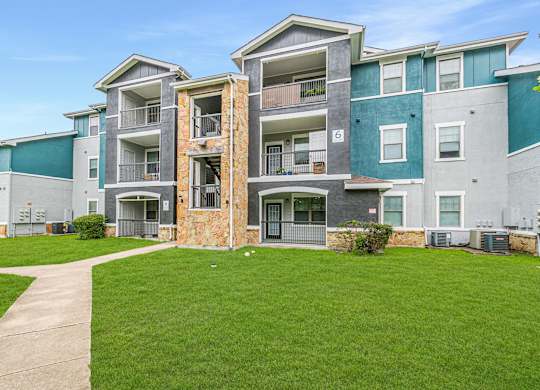 Apartment building with a green lawn in front.