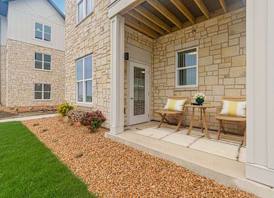 A house with a white door and two chairs on the porch.