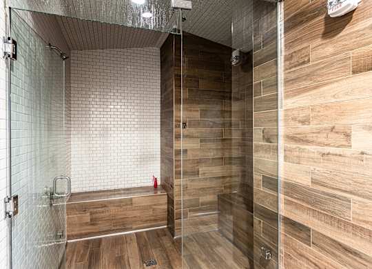 A shower with a glass door and a wooden wall.