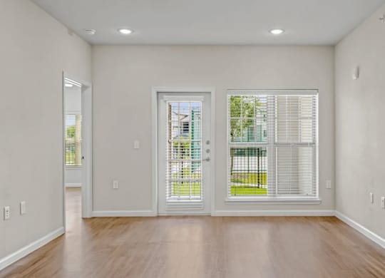 an empty living room with windows and wood floors at Cypress Creek at River Oaks, Texas, 75165