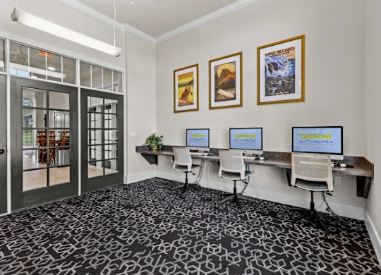 a conference room with three computer monitors on a desk at Cypress Creek at River Oaks, Waxahachie, TX