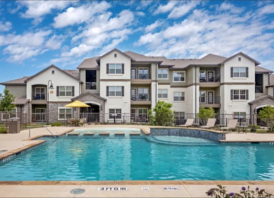a swimming pool with an apartment building in the background at Cypress Creek at River Oaks, Waxahachie, 75165