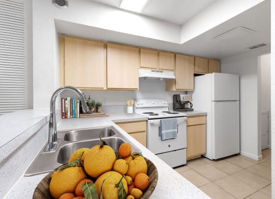a kitchen with white appliances and a bowl of fruit