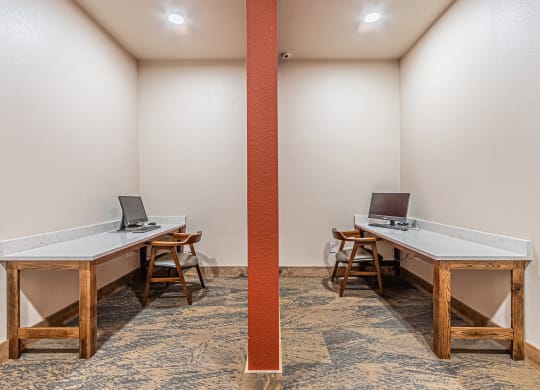 a writers room with two tables with computers and chairs
