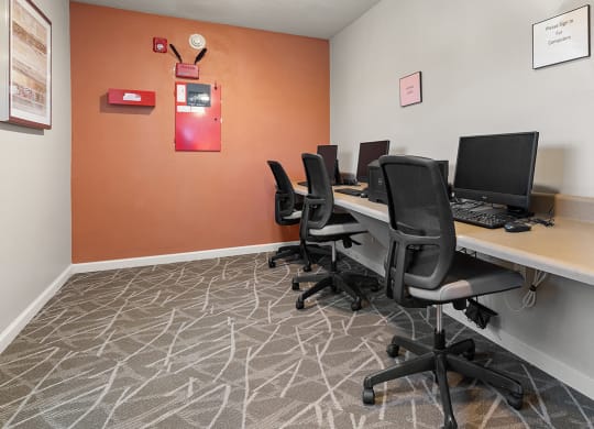 a computer room with desks and chairs and a bulletin board on the wall