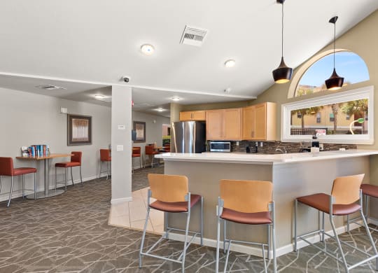 a clubhouse with a bar and a kitchen with stools