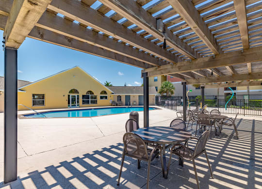 a patio with tables and chairs next to a swimming pool