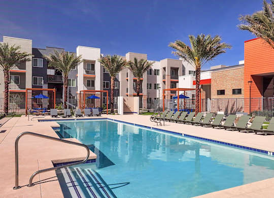A swimming pool in front of a building with palm trees.