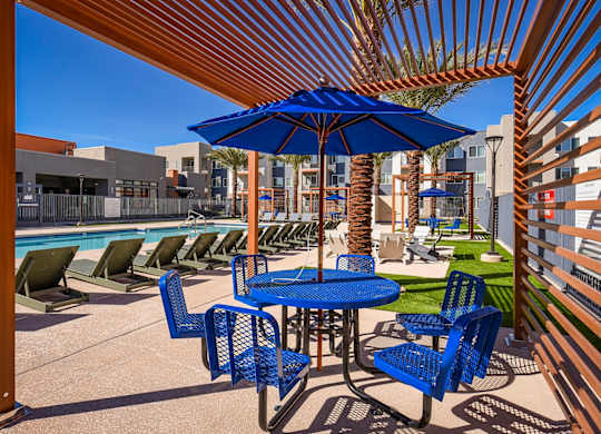 A blue umbrella is on a table with chairs around it.