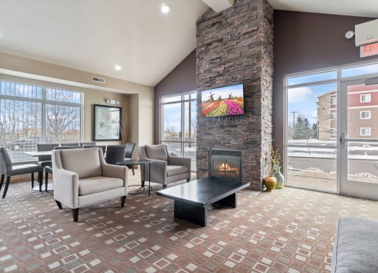 a lobby with couches chairs and a fireplace    and a glass door