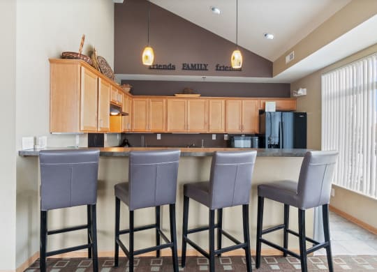 a kitchen with three bar stools in front of a counter with three chairs