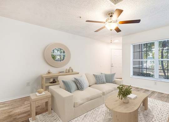 A living room with a beige couch, a wooden coffee table, and a round mirror on the wall.