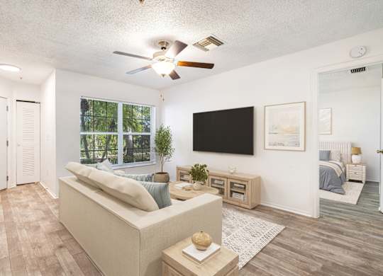A living room with a couch, a television, and a ceiling fan.