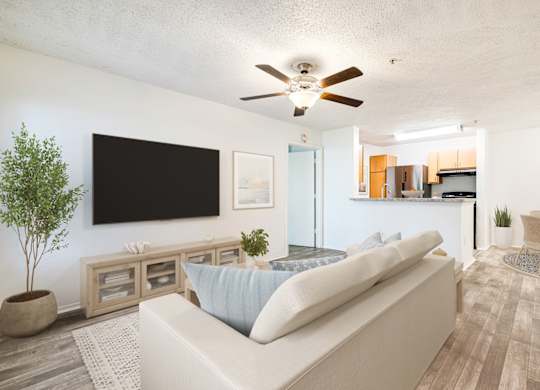 A living room with a white couch and a flat screen TV mounted on the wall.