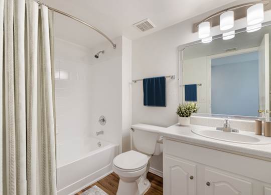A white bathroom with a toilet, sink, and shower.