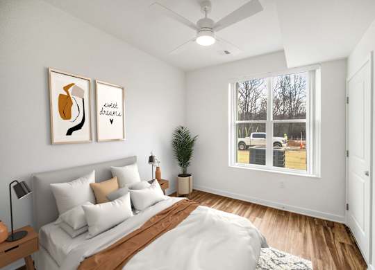 A bedroom with a bed, pillows, a ceiling fan, and two framed pictures on the wall.at Creekridge on The Park, Charlotte, NC