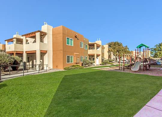 A playground with a slide is in front of a building.
