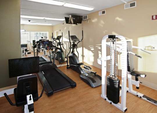 A gym with a variety of equipment including a treadmill, weights, and a television.