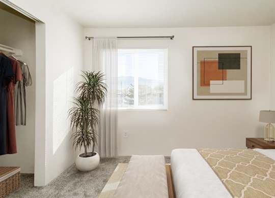 A bedroom with a large bed, a potted plant, and a painting on the wall.