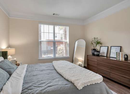 A bedroom with a large bed and a window with blinds.