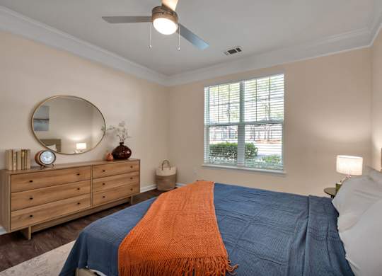 A bedroom with a bed, dresser, and window.