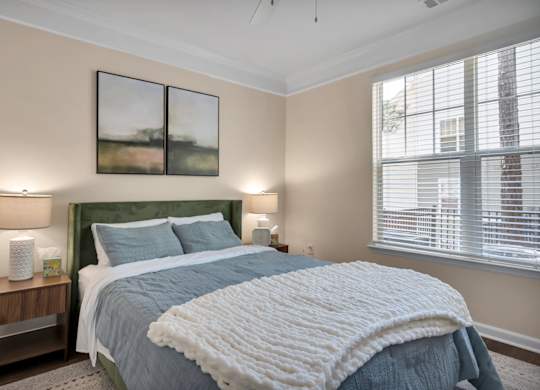 A bedroom with a large bed and two lamps on side tables.