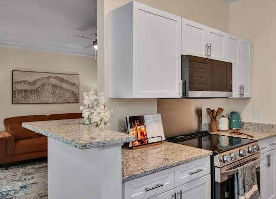 A kitchen with granite countertops and white cabinets.