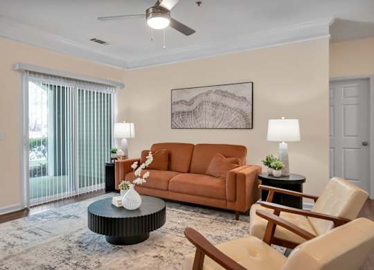 A living room with a brown couch, a coffee table, and a ceiling fan.