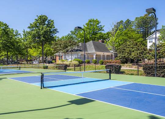 A tennis court surrounded by trees and a building in the background.