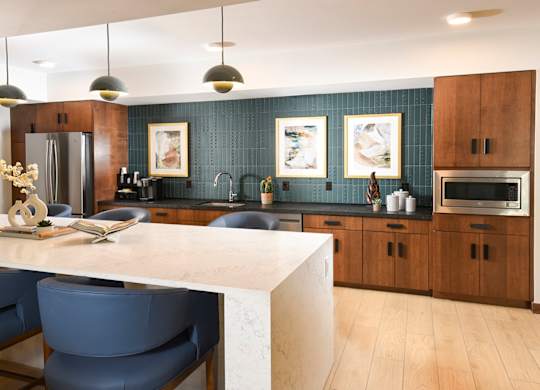 A modern kitchen with a white countertop and blue chairs.