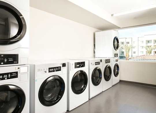 A row of white front load washing machines in a laundry room.