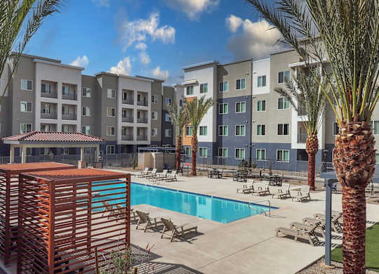 A pool area with palm trees and a building in the background.