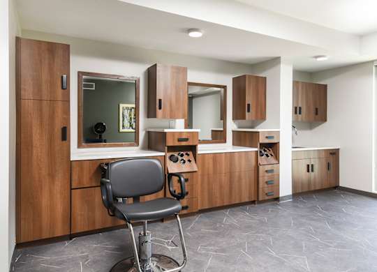 A chair is in front of a wooden cabinet with a mirror.