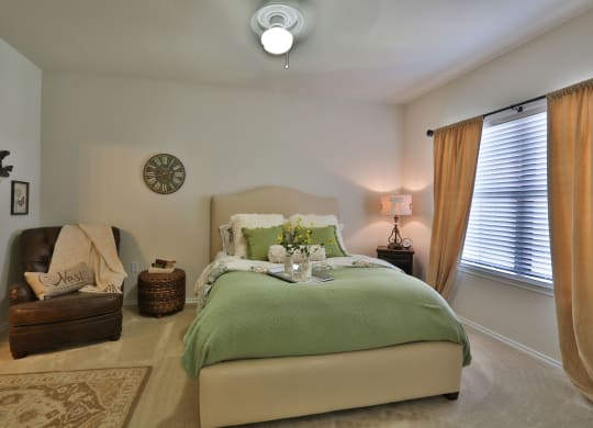 a bedroom with a bed and a chair and a clock on the wall