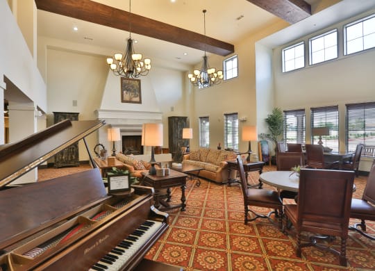 a large living room with a piano and a fireplace at Cedars of Elk Drive 55+ Apartments, Burleson