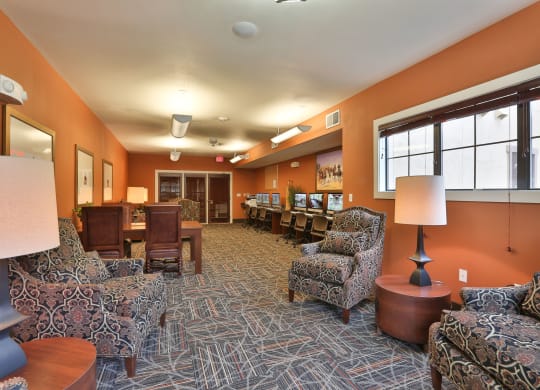 a lounge area with chairs and tables and a large window at Cedars of Elk Drive 55+ Apartments, Burleson, 76028