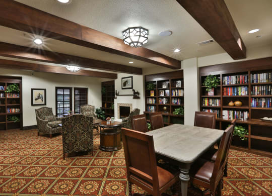 a library with a table and chairs and a fireplace at Cedars of Elk Drive 55+ Apartments, Burleson Texas