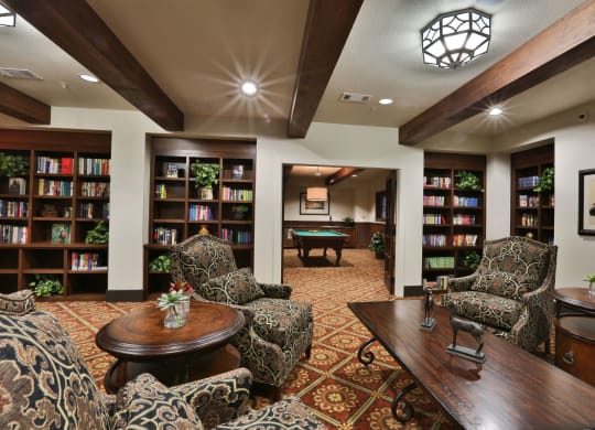 a game room with a pool table and book shelves at Cedars of Elk Drive 55+ Apartments, Burleson