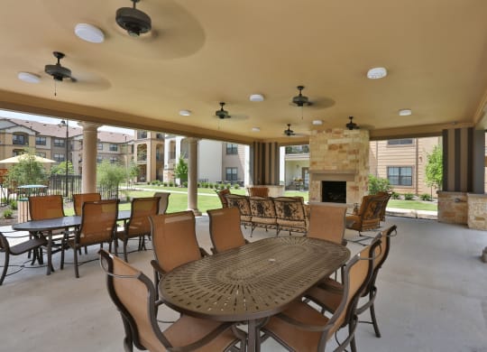 a patio with tables and chairs and a fireplace at Cedars of Elk Drive 55+ Apartments, Texas, 76028