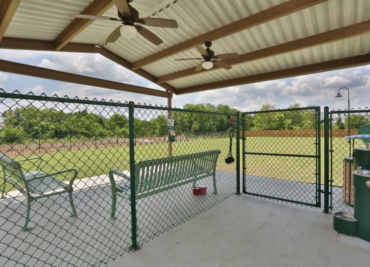 a patio with a bench and a chain link fence at Cedars of Elk Drive 55+ Apartments, Burleson, TX
