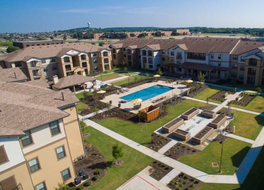 an aerial view of an apartment complex with a swimming pool at Cedars of Elk Drive 55+ Apartments, Burleson, TX 76028