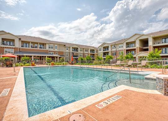 a swimming pool with an apartment building in the background at Mariposa at South Broadway, Joshua