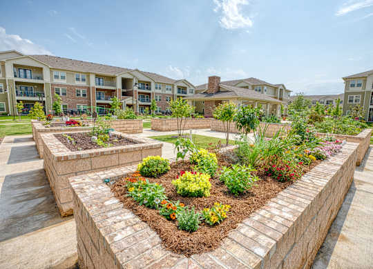 an aerial view of a community garden with apartments in the background at Mariposa at South Broadway, Joshua, 76058