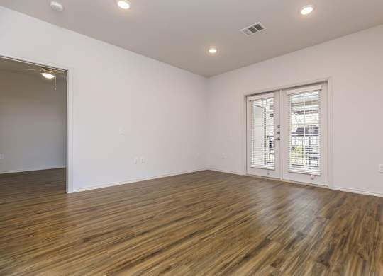 a living room with white walls and wood flooring and a door to a balcony at Mariposa at Westchester, Texas