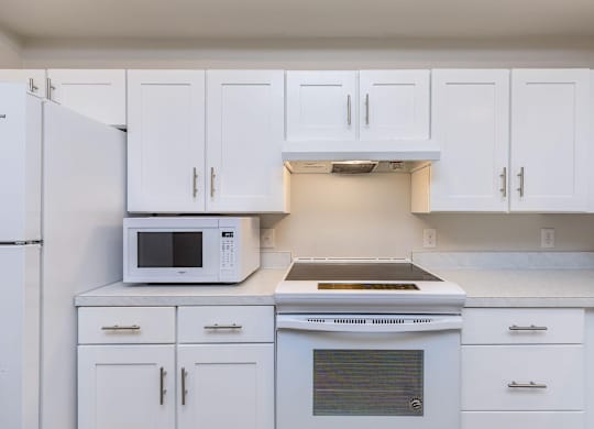 a kitchen with white cabinets and a microwave and a stove at Mariposa at Westchester, Texas, 75052