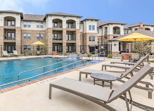 our apartments offer a swimming pool with lounge chairs and umbrellas at Mariposa at Westchester, Grand Prairie, TX