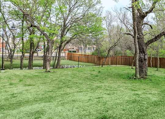 the backyard of a home with a fenced in yard and trees at Mariposa at Westchester, TX 75052 