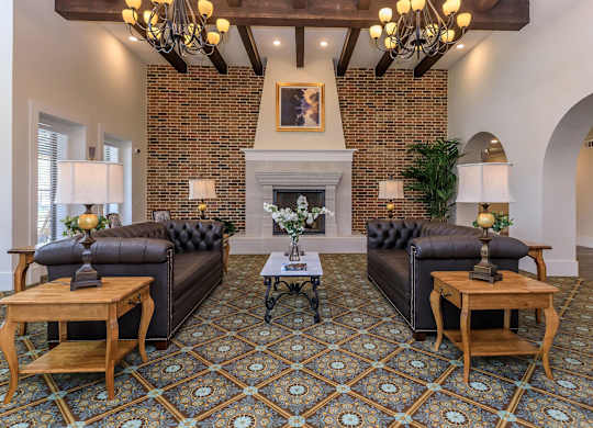 a living room with leather couches and a brick fireplace at Mariposa at Westchester, Grand Prairie