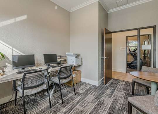 A room with a desk, chairs, and a plant.
